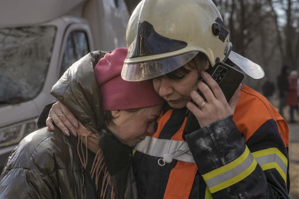 A firefighter comforts a woman outside a destroyed apartment building after a bombing in a residential area in Kyiv, Ukraine, Tuesday, March 15, 2022. Russia's offensive in Ukraine has edged closer to central Kyiv with a series of strikes hitting a residential neighborhood as the leaders of three European Union member countries planned a visit to Ukraine's embattled capital. (AP Photo/Vadim Ghirda)