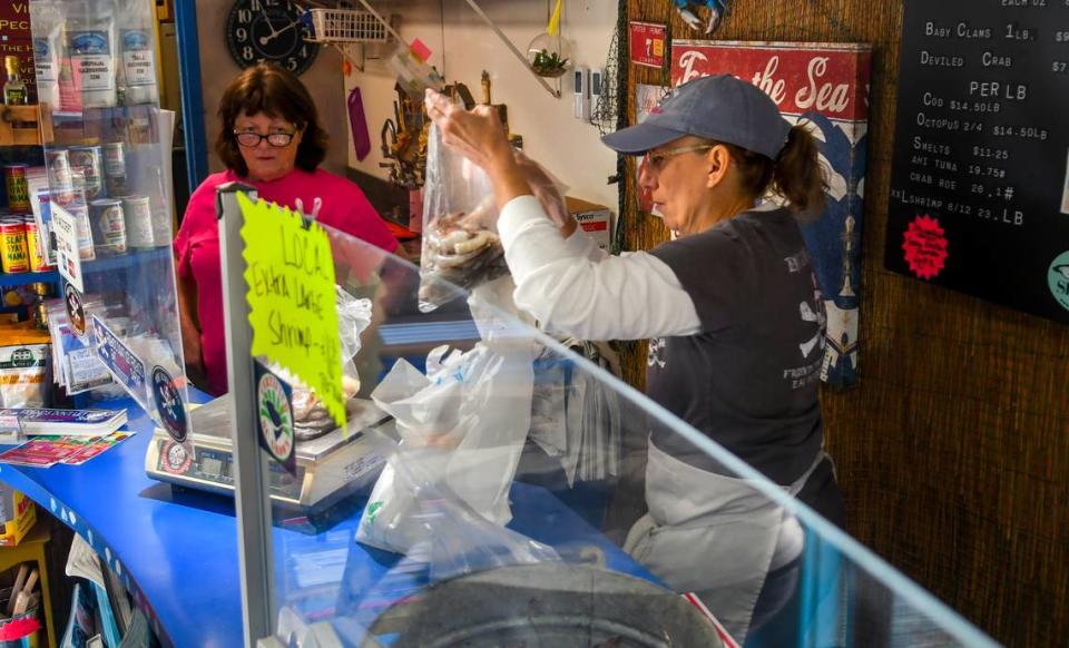 Janice Heuck, left, watches as fellow employee Colleen Wooby weighs out locally caught shrimp for a customer on Friday, March 24, 2023 at Benny Hudson Seafood on Hilton Head Island.