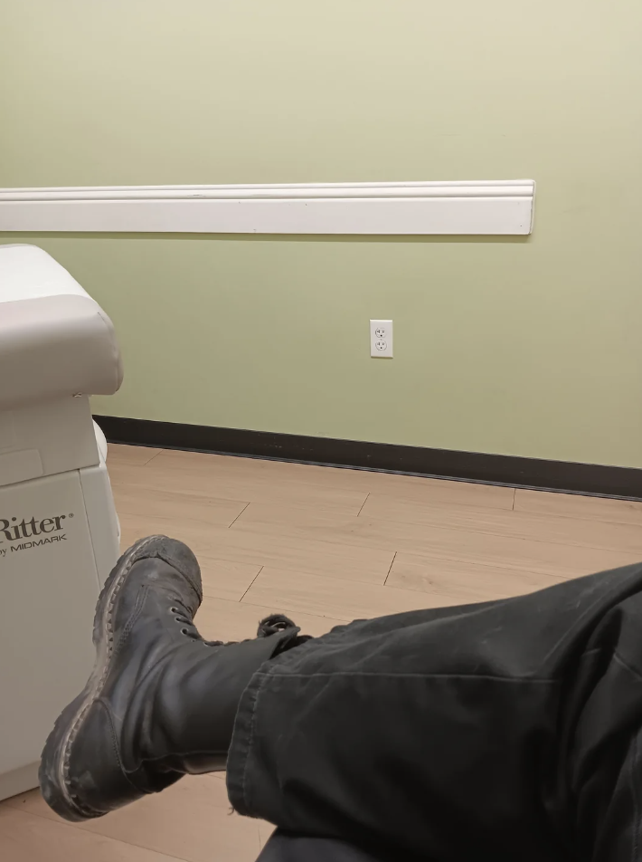 Person's feet in boots resting on a medical examination bed in a room