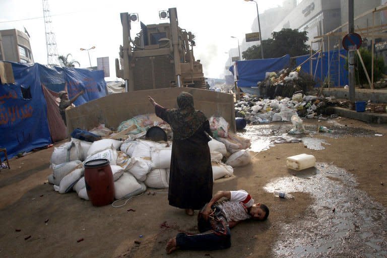 An Egyptian woman tries to stop a military bulldozer from hurting a wounded youth during clashes near Rabaa al-Adawiya mosque in eastern Cairo on August 14, 2013