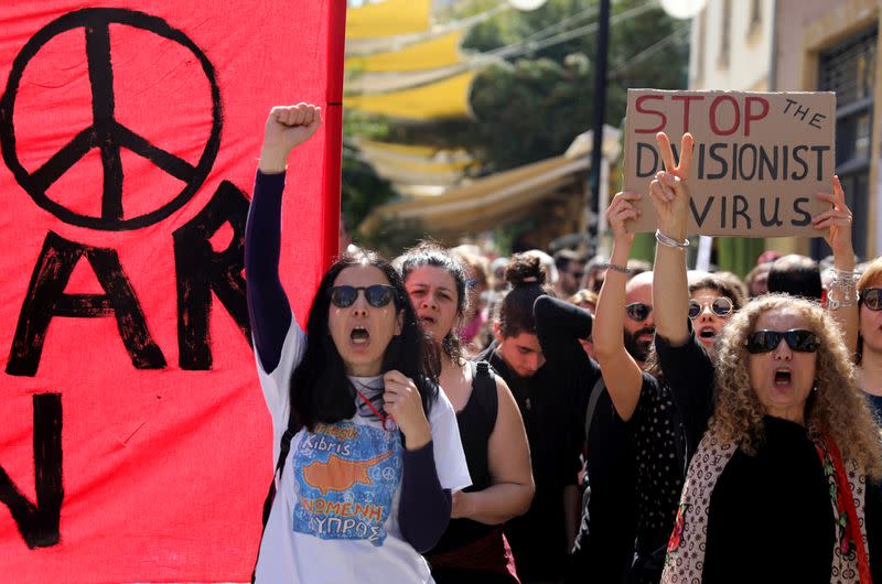 Greek Cypriots shout slogans at the Ledra checkpoint of the U.N.-controlled buffer zone, after authorities declared the crossing temporarily shut to curb any potential spread of coronavirus, in Nicosia