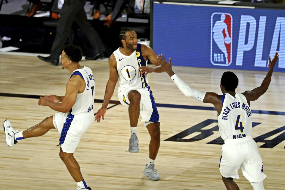 Indiana Pacers forward T.J. Warren (1) celebrates with guards Malcolm Brogdon (7) and Victor Oladipo (4) after a play against the Los Angeles Lakers during an NBA basketball game Saturday, Aug. 8, 2020, in Lake Buena Vista, Fla. (Kim Klement/Pool Photo via AP)