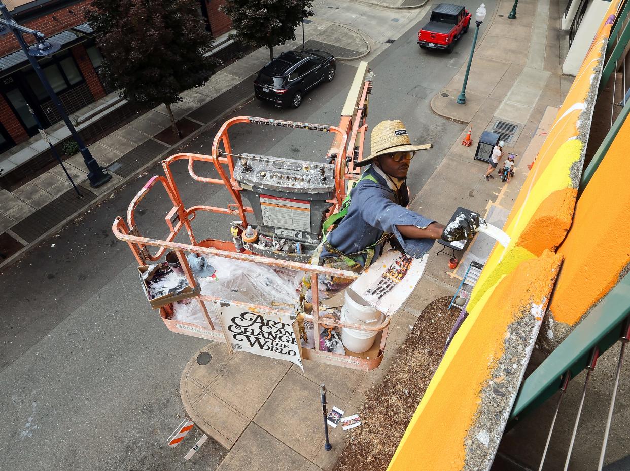 Artist KaDavien Baylor works on his mural located on the parking garage at the corner of Washington and Fourth in downtown Bremerton on Thursday, Aug 15, 2024.