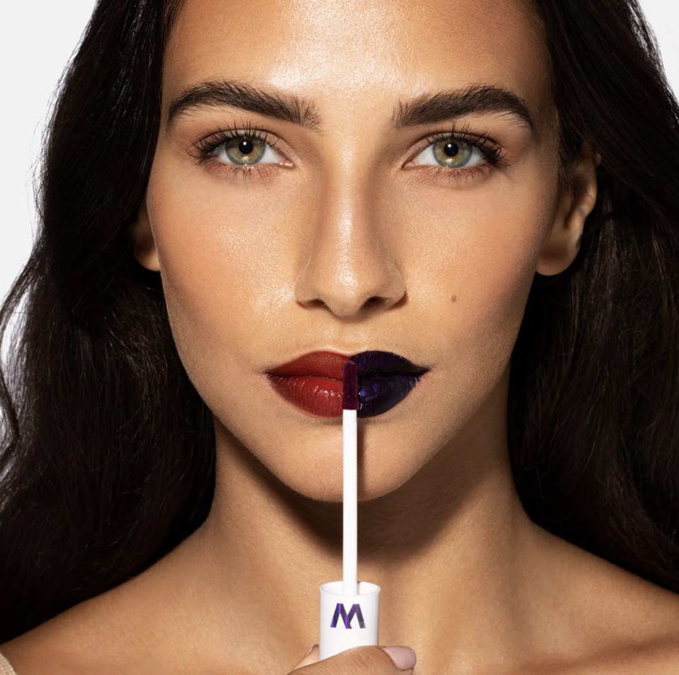  brunette woman applying Wonder Blading Lip Stain Masque on red and blue lips (Photo via Wonderskin)