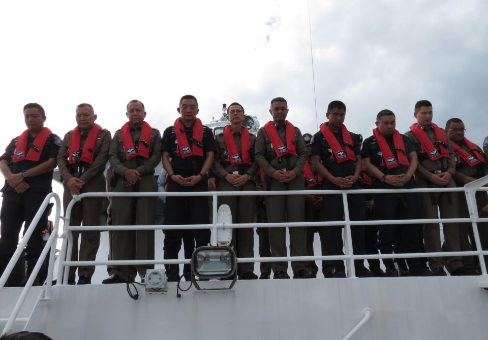 Police pause for a moment in honor as a crane boat raises the tour boat named the Pheonix from the sea floor, Saturday, Nov. 17, 2018, in Phuket, Thailand, after sinking in rough weather killing 47 tourists. The tour boat was one of two boats that sank off the popular tourist island in stormy weather on July 5, 2018. (AP Photo)