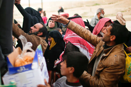 Displaced Iraqis help each each other to get onto a truck to be carried to a safe place, as Iraqi forces battle with Islamic State militants, in western Mosul, Iraq March 8, 2017. REUTERS/Suhaib Salem