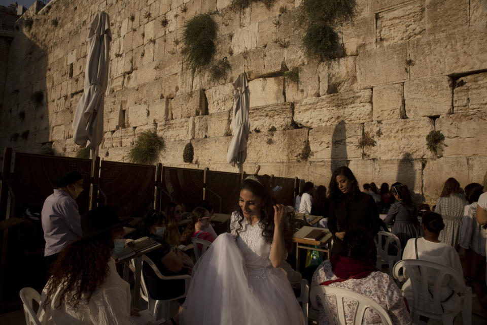 A bride leaves after praying and posing for wedding photos at the Western Wall, the holiest site where Jews can pray, in the shadow of the Mughrabi Bridge, a wooden pedestrian bridge connecting the wall to the Al Aqsa Mosque compound, in Jerusalem's Old City, Tuesday, July 20, 2021. The rickety bridge allowing access to Jerusalem's most sensitive holy site is at risk of collapse, according to experts. But the flashpoint shrine's delicate position at ground-zero of the Israeli-Palestinian conflict has prevented its repair for more than a decade. (AP Photo/Maya Alleruzzo)