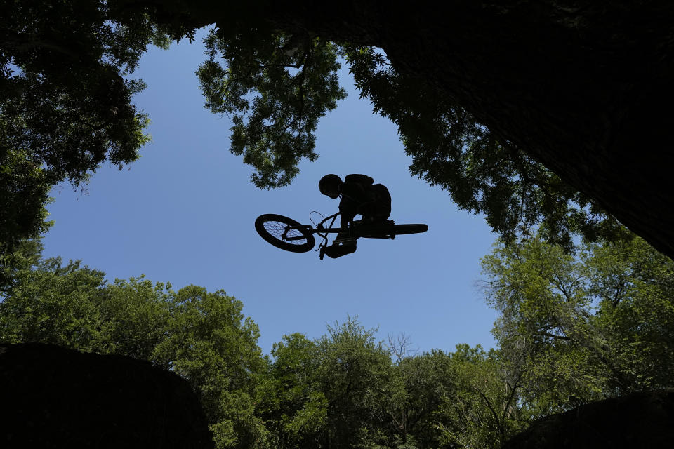 Issac Bowman rides his bike on dirt trails in Austin, Texas, Wednesday, June 28, 2023. Meteorologists say scorching temperatures brought on by a heat dome have taxed the Texas power grid and threaten to bring record highs to the state. (AP Photo/Eric Gay)