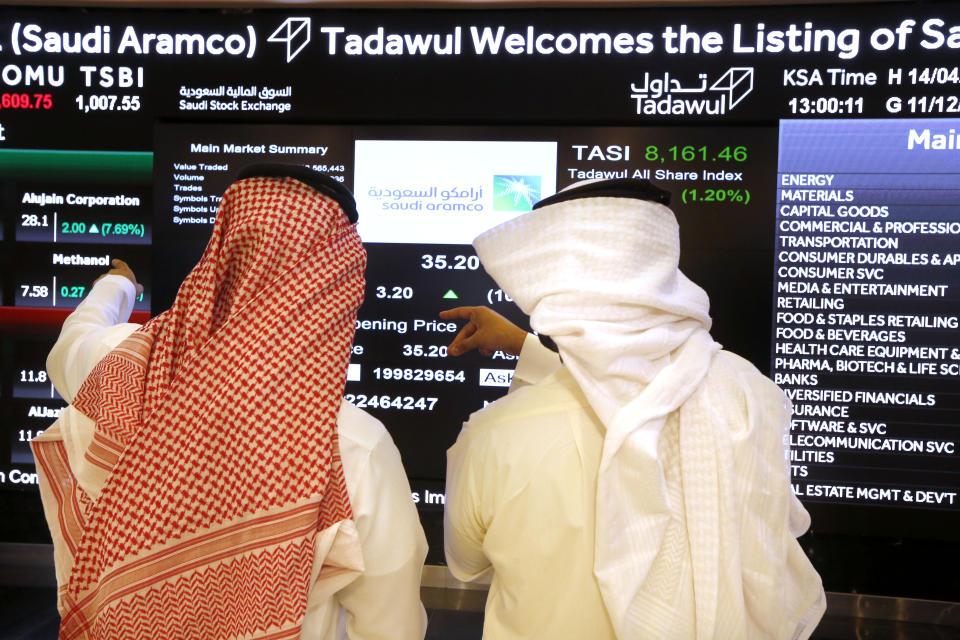 Saudi stock market officials watch the market screen displaying Saudi Arabia's state-owned oil company Aramco after the debut of Aramco's initial public offering (IPO) on the Riyadh's stock market in Riyadh, Saudi Arabia, Wednesday, Dec. 11, 2019. (AP Photo/Amr Nabil)