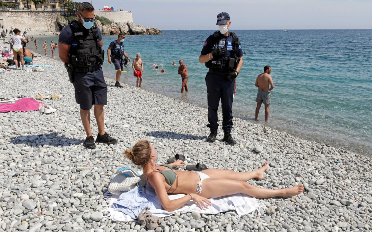 Municipal police officers wearing face masks talk to a woman, at the Promenade des Anglais, as they check that safety restrictions are being practised, after France reopened its beaches to the public as part of the softening of its strict lockdown rules - Eric Gaillard/Reuters