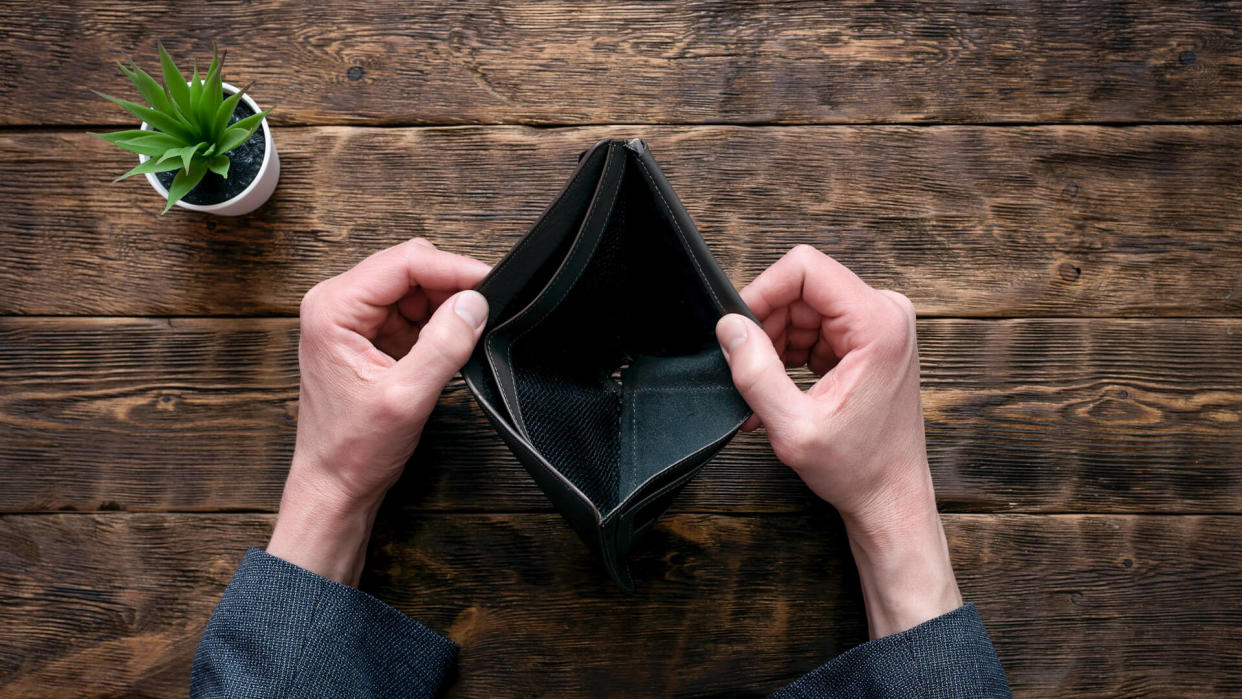 Empty wallet in hands on an office table shutterstock_1347772349