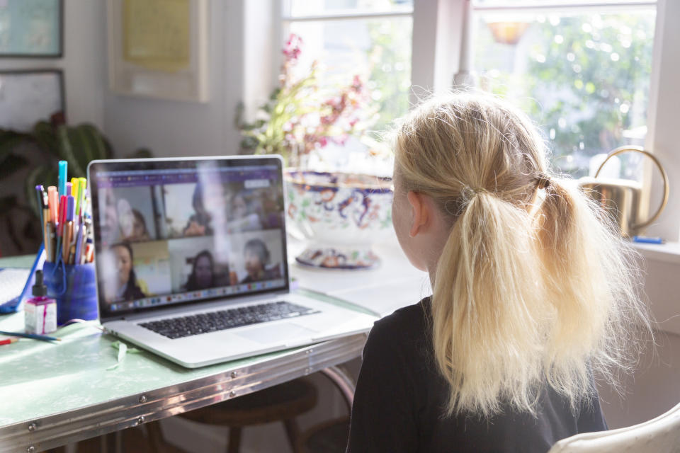 Girl attending an online class on a laptop at a home desk