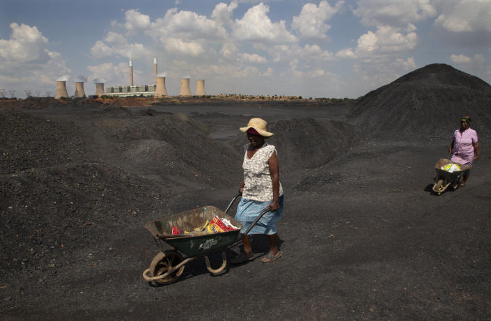 Women push wheelbarrows atop a coal mine dump at the coal-powered Duvha power station, near Emalahleni east of Johannesburg, South Africa on Nov. 17, 2022. (Denis Farrell/AP)