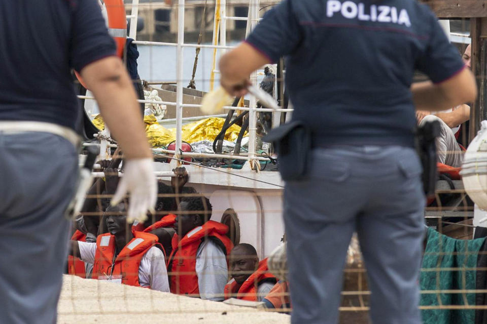 Italian police officers stand in front of the the German rescue boat Eleonore as migrants wait to disembark, in the port of Pozzallo, Sicily, Southern Italy, Monday, Sept. 2, 2019. Italy’s interior minister is vowing to make a charity boat with some 100 rescued migrants aboard pay dearly for docking in Sicily in defiance of a government ban. (Francesco Ruta/ANSA via AP)