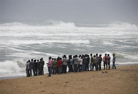 People watch as waves from the Bay of Bengal approach the shore at Podampata village in Ganjam district, Odisha October 11, 2013. REUTERS/Stringer