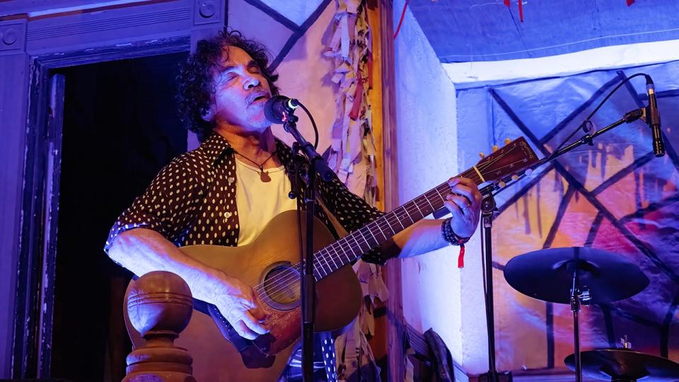 John Oates singing and playing guitar on stage