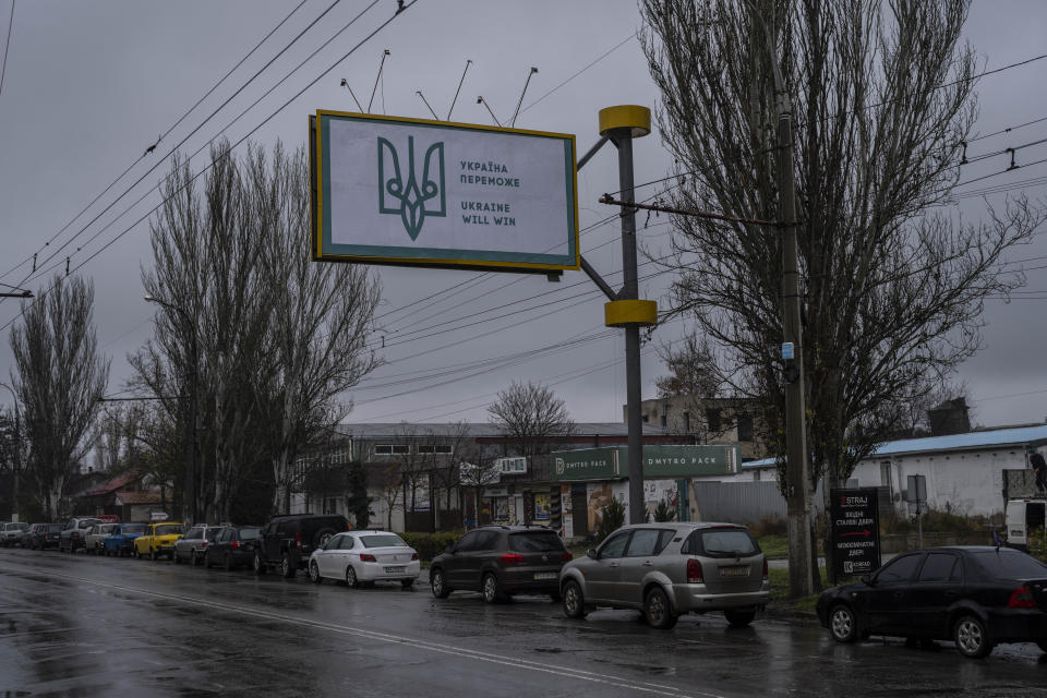 Cars line up to refuel under a newly placed Ukrainian billboard in Kherson, southern Ukraine, Friday, Nov. 25, 2022. (AP Photo/Bernat Armangue)