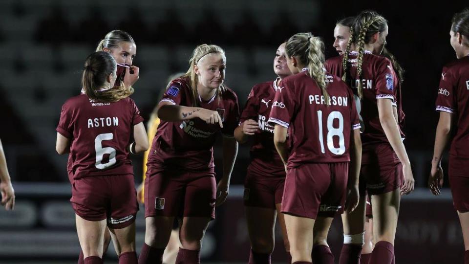 Bianca Luttman of Northampton Town gives her team mates instructions on the pitch - all are dressed in claret-coloured football strip with names and numbers on the back of the shirts