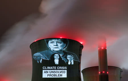 Greenpeace activists project images of German Chancellor Angela Merkel (top), German Economy minister Peter Altmaier, SPD chairwoman Andrea Nahles and German Transport minister Andreas Scheuer (L-R) with a slogan onto a cooling tower of the brown coal power plant of RWE, one of Europe's biggest utilities in Neurath, north-west of Cologne, Germany, December 14, 2018. REUTERS/Wolfgang Rattay