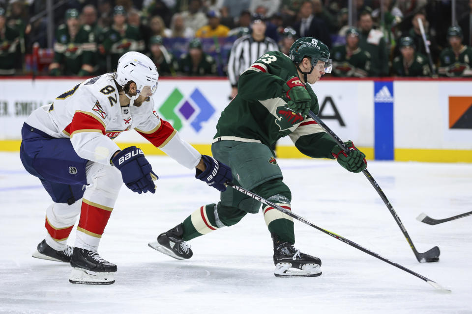 Minnesota Wild center Marco Rossi, right, shoots while Florida Panthers center Kevin Stenlund (82) defends during the second period of an NHL hockey game Thursday, Oct. 12, 2023, in St. Paul, Minn. (AP Photo/Matt Krohn)