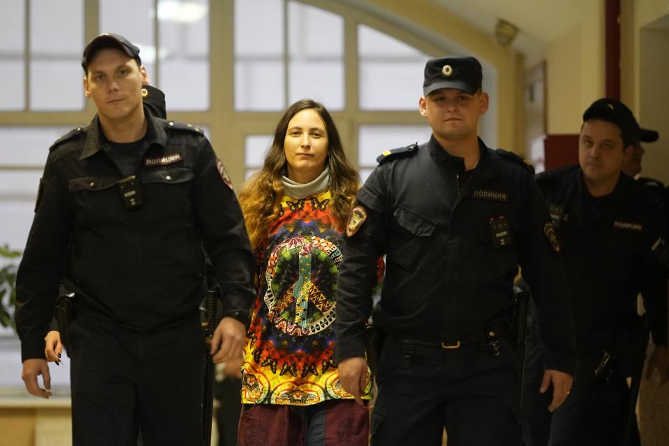 Sasha Skochilenko, a 33 year-old artist and musician, second left, is escorted by officers to the court room for a hearing in the Vasileostrovsky district court in St. Petersburg, Russia, Monday, Nov. 13, 2023. A court in St Petersburg has to deliver a verdict to a young artist Sasha Skochilenko on charges of spreading "fakes" about the Russian military after she replaced four small price tags in a St. Petersburg supermarket with anti-war slogans. The prosecution asked to sentence her to 8 years in prison. (AP Photo/Dmitri Lovetsky)