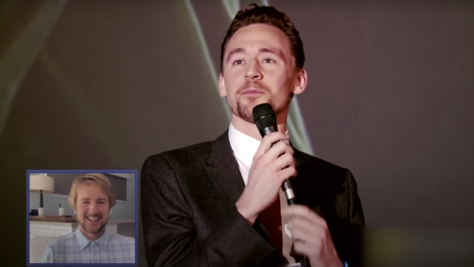 Tom Hiddleston talks into a microphone, while Owen Wilson, in a small box, watches