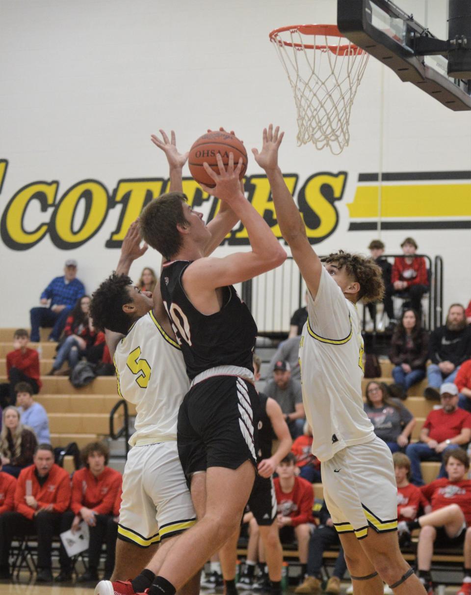 Fairfield Union's Caleb Schmelzer puts up a shot against Tri-Valley's Terrell Darden (5) and Nohah Nichols (12) in Thursday's game. The Scotties won 54-49.