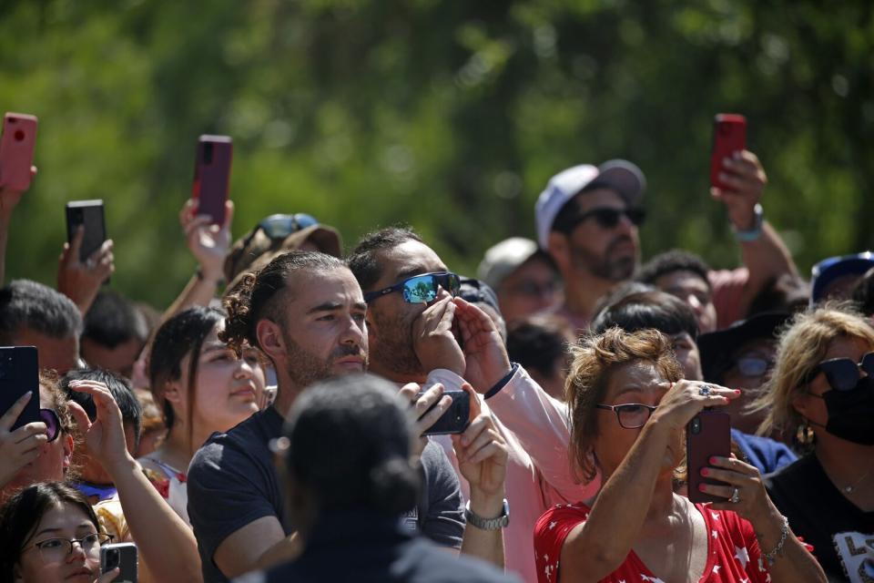 Uvalde residents watch and some boo at Texas Governor Greg Abbott as he arrives at the memorial outside Robb Elementary School to honor the victims killed in this week's school shooting in Uvalde, Texas