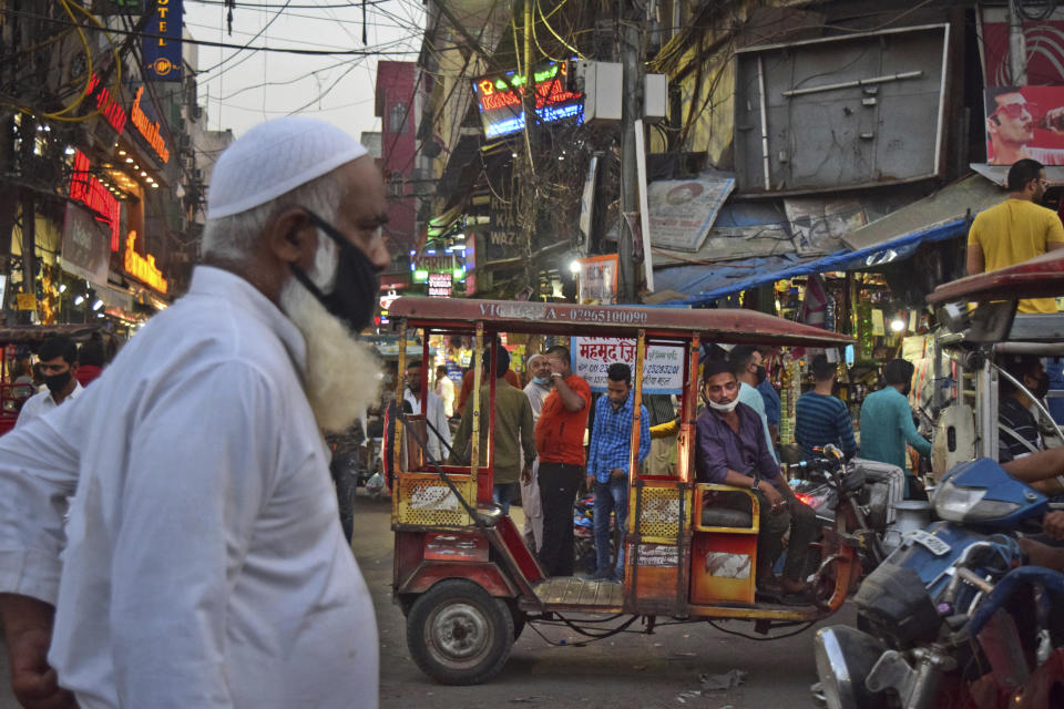 A driver of an e-rickshaw waits for passengers at a busy market place in New Delhi, India, Sunday, March 28, 2021. India has ambitions to expand use of electric vehicles to wean itself from polluting fossil fuels, but EVs are still a rarity on its congested highways. A lack of charging stations and poor quality batteries are discouraging drivers from switching over. (AP Photo/Neha Mehrotra)