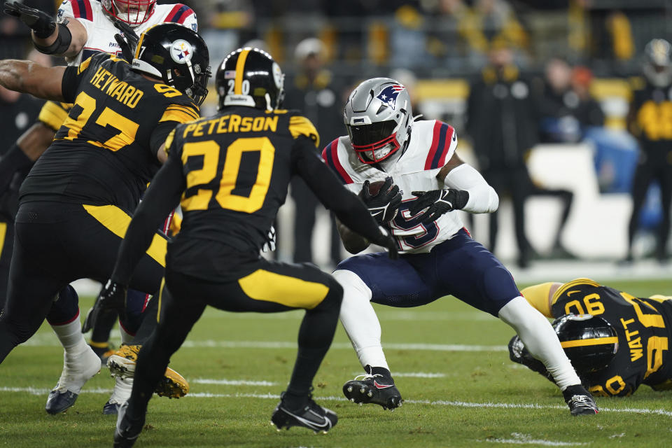 New England Patriots running back Ezekiel Elliott runs with the ball as Pittsburgh Steelers defensive tackle Cameron Heyward (97) and cornerback Patrick Peterson (20) defend during the first half of an NFL football game on Thursday, Dec. 7, 2023, in Pittsburgh. (AP Photo/Matt Freed)