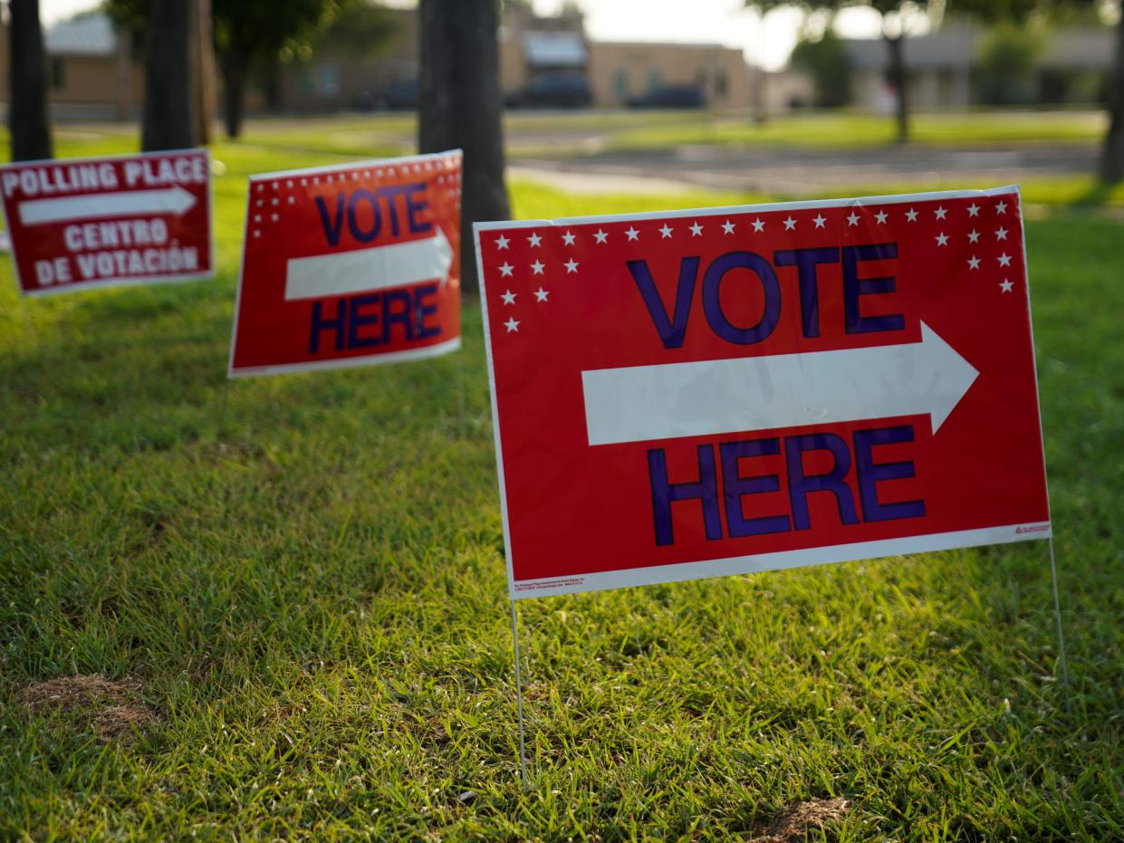 Red yard signs in Texas that read "vote here."