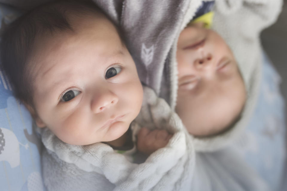 Fraternal Twin Infant boys sleep next to each other at home.