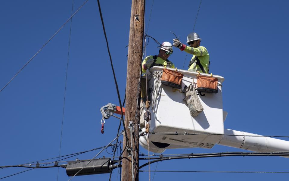 FILE - In this Oct. 25, 2019, file photo, Southern California Edison crews replace power lines that were damaged from the Tick Fire in Santa Clarita, Calif. Southern California Edison will pay $2.2 billion to settle insurance claims from a deadly, destructive wildfire sparked by its equipment in 2018, the utility announced Monday, Jan. 25, 2021. (AP Photo/ Christian Monterrosa, File)