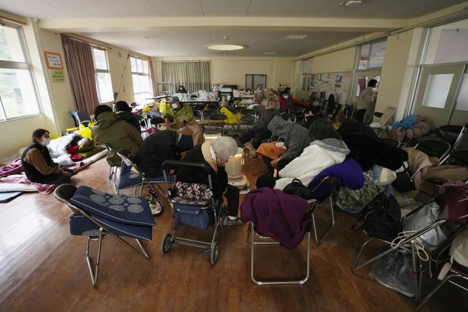 Evacuees rest surrounding a stove at a temporary evacuation center in Suzu in the Noto peninsula facing the Sea of Japan, northwest of Tokyo, Wednesday, Jan. 3, 2024, following Monday's deadly earthquake. (AP Photo/Hiro Komae)