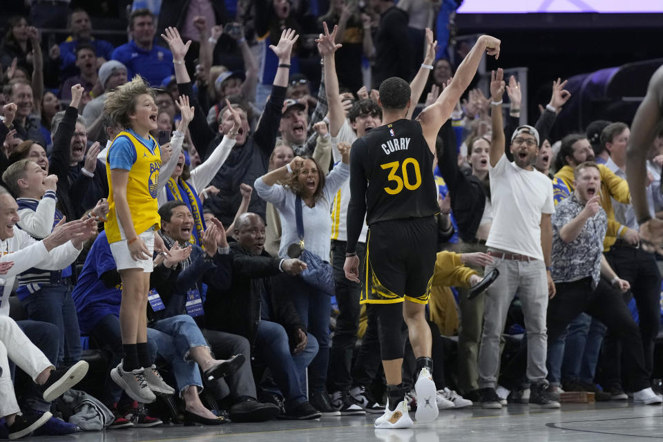 Fans cheer as Golden State Warriors guard Stephen Curry (30) reacts after making a 3-point basket during overtime of an NBA basketball game against the Milwaukee Bucks in San Francisco, Saturday, March 11, 2023. (AP Photo/Jeff Chiu)