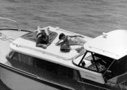 <p>Elizabeth Taylor lounges on the deck of her yacht with actor Richard Burton. The actress wears a strapless bikini top and floral pants. </p>