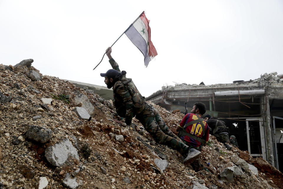 FILE - In this Dec. 5, 2016 file photo, a Syrian army soldier places a Syrian national flag during a battle with rebel fighters at the Ramouseh front line, east of Aleppo, Syria. Syrians are marking 10 years since peaceful protests against President Bashar Assad's government began in March 2011, touching off a popular uprising and a war that turned into the worst humanitarian crisis of the 21st century. (AP Photo/Hassan Ammar, File)