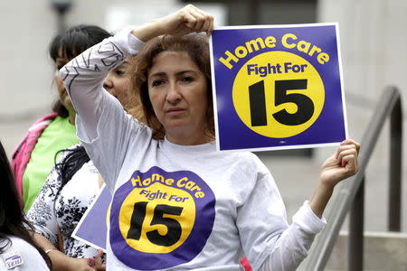 Ingrid Alarcon holds a sign before the Los Angeles City Council approved a proposal to increase the minimum wage to $15.00 per hour in Los Angeles, California June 3, 2015. REUTERS/Jonathan Alcorn