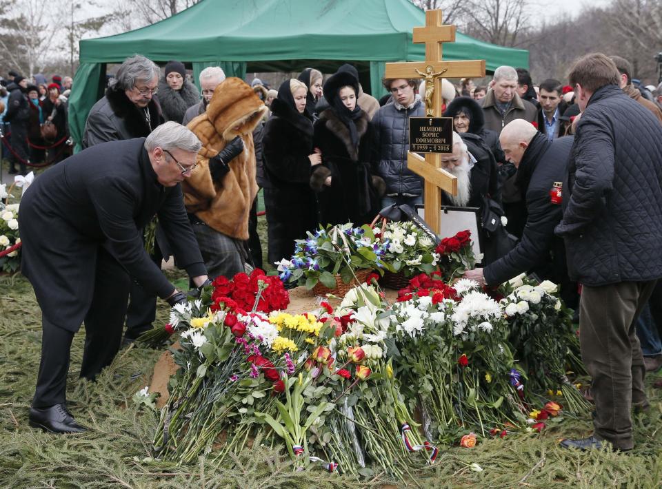 Mourners, including Mikhail Kasyanov (L), an opposition leader and former Russian prime minister, lay flowers at the grave of Russian leading opposition figure Boris Nemtsov during his funeral in Moscow, March 3, 2015. Thousands of Russians, many carrying red carnations, queued on Tuesday to pay their respects to Boris Nemtsov, the Kremlin critic whose murder last week showed the hazards of speaking out against Russian President Vladimir Putin. (REUTERS/Maxim Shemetov)
