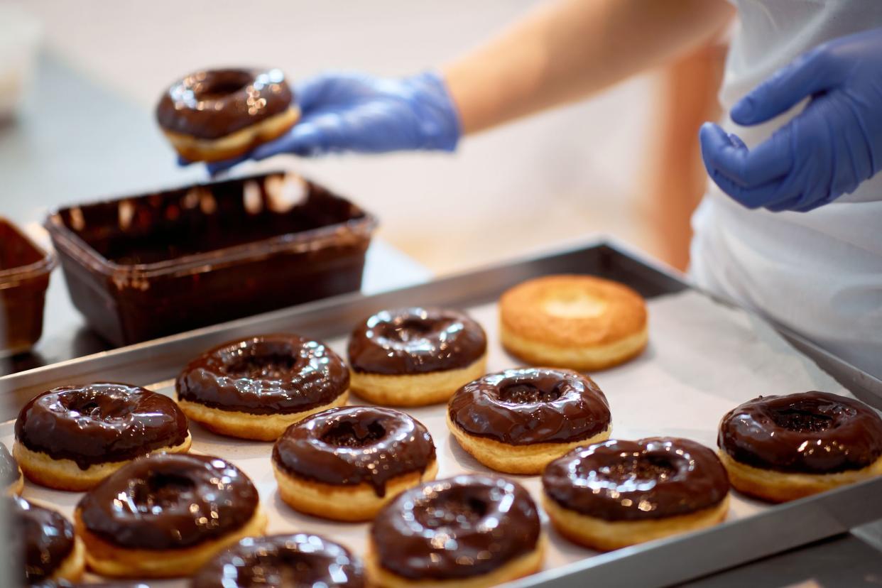 Chocolate topping on donuts in a working atmosphere in a candy workshop. Pastry, dessert, sweet, making