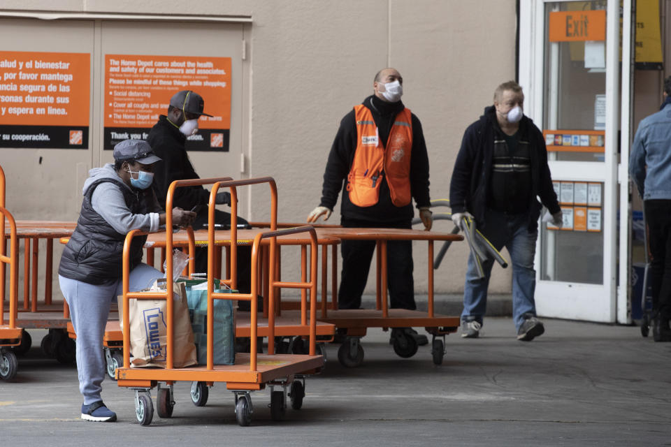 Home Depot customers carry their purchases as they leave the store, Friday, April 3, 2020 during the coronavirus pandemic in New York. (AP Photo/Mark Lennihan)