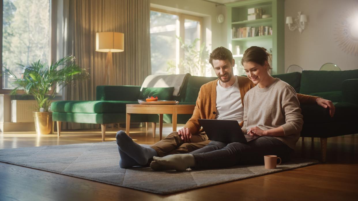  A couple sitting looking happy watching a video on a laptop. 