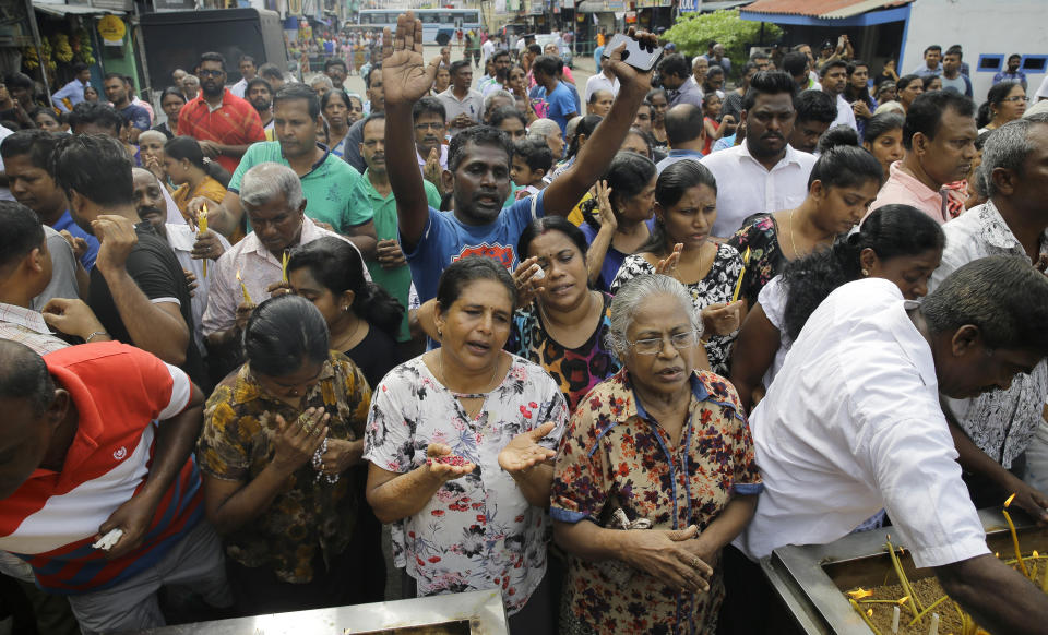 Sri Lankan Catholics pray standing on a road during a brief holly mass held outside the exploded St. Anthony's Church marking the seventh day of the Easter Sunday attacks in Colombo, Sri Lanka, Sunday, April 28, 2019. Sri Lanka's Catholics on Sunday awoke preparing to celebrate Mass in their homes by a televised broadcast as churches across the island shut over fears of militant attacks, a week after the Islamic State-claimed Easter suicide bombings. (AP Photo/Eranga Jayawardena)