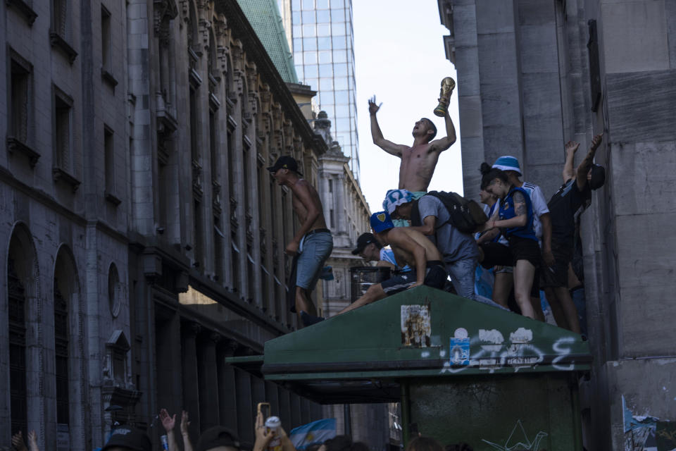 Soccer fans continue to celebrate outside the Casa Rosada presidential palace, despite waiting for hours for a homecoming parade for the players who won the World Cup title that was abruptly cut short, in Buenos Aires, Argentina, Tuesday, Dec. 20, 2022. A parade to celebrate the Argentine World Cup champions was abruptly cut short Tuesday as millions of people poured onto thoroughfares, highways and overpasses in a chaotic attempt to catch a glimpse of the national team. (AP Photo/Rodrigo Abd)