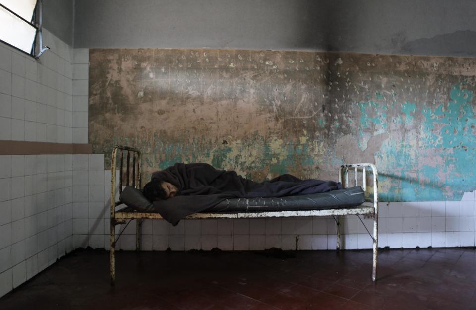 In this May 29, 2013 photo, a patient sleeps in a bedroom at the Neuro-Psychiatric Hospital in Asuncion, Paraguay. Paraguay's only public psychiatric hospital has no money for heating to protect patients from the biting chill during the winter months. (AP Photo/Jorge Saenz)