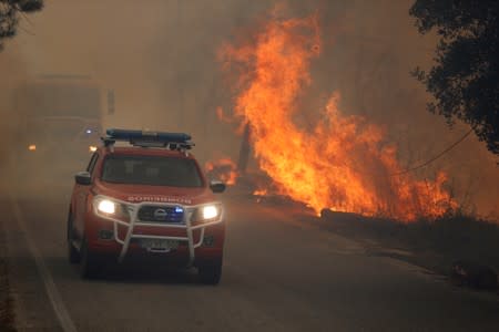 Firefighters drive through smoke from a forest fire in Chaveira