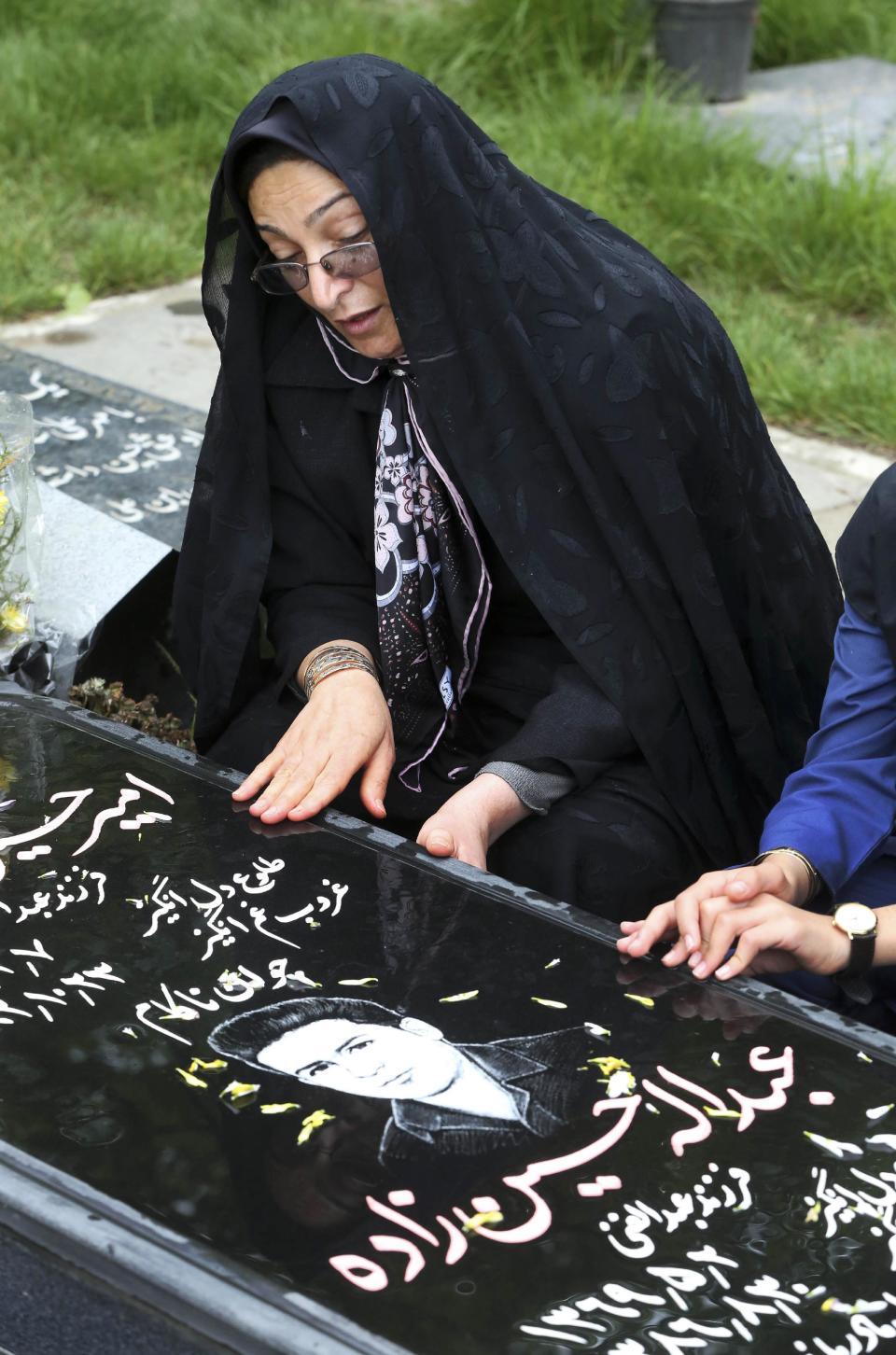 In this picture taken on Monday, April 28, 2014, Iranian woman Samereh Alinejad prays at the grave of her sons Amir Hossein and Abdollah in a cemetery in the city of Royan about 146 miles (235 kilometers) north of the capital Tehran, Iran. Amir Hossein was killed in a motorcycle crash and Abdollah was killed in a street brawl. Alinejad tells The Associated Press that she had felt she could never live with herself if the man who killed her son Abdollah were spared from execution. But in the last moment, she pardoned him in an act that has made her a hero in her hometown, where banners in the streets praise her family’s mercy. (AP Photo/Vahid Salemi)