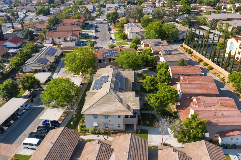 An aerial view of homes with solar panels on their roofs.