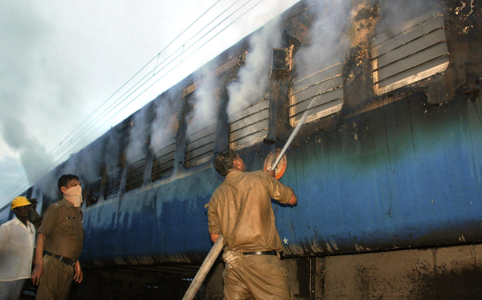 An Indian fire official douses fire coming out from a coach of a passenger train at Nellor nearly 500 kilometers (310 miles) south of Hyderabad, India, Monday, July 30, 2012. A fire swept through a train car packed with sleeping passengers in southern India on Monday, killing at least 47 people and sending panicked survivors rushing for the only clear exit once the train stopped, officials said. (AP Photo)