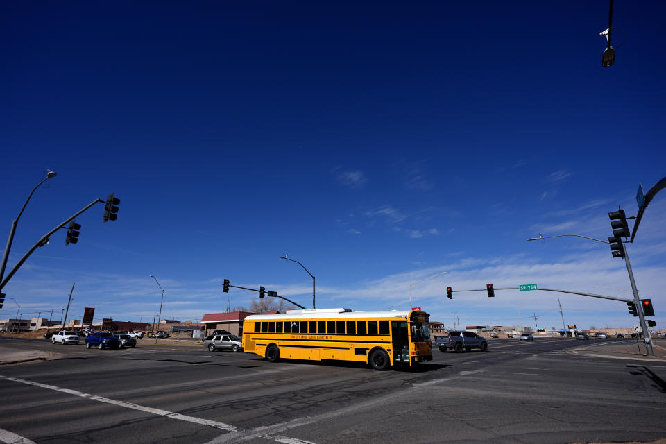 A school bus crosses over Route 160 from the Navajo Nation, left, onto the Hopi reservation, right, Monday, March 4, 2024, in Tuba City, Ariz. U.S. 160 is the de facto border between the Navajo and Hopi Indian reservations and two time zones. Mind-bending time calculations is what people in the largest Native American reservation in the U.S. have to endure every March through November. (AP Photo/Matt York)